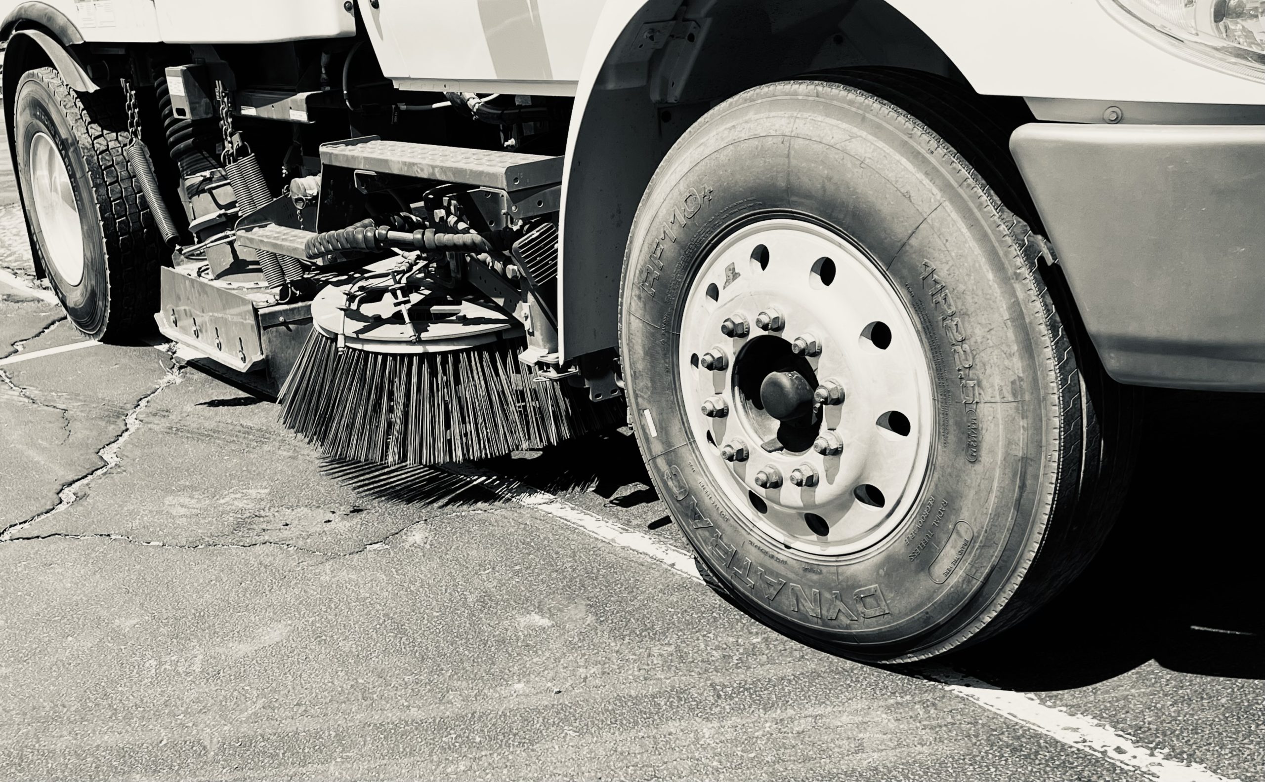 Close-up image of a truck and broom on the ground, showcasing equipment used for erosion control services.