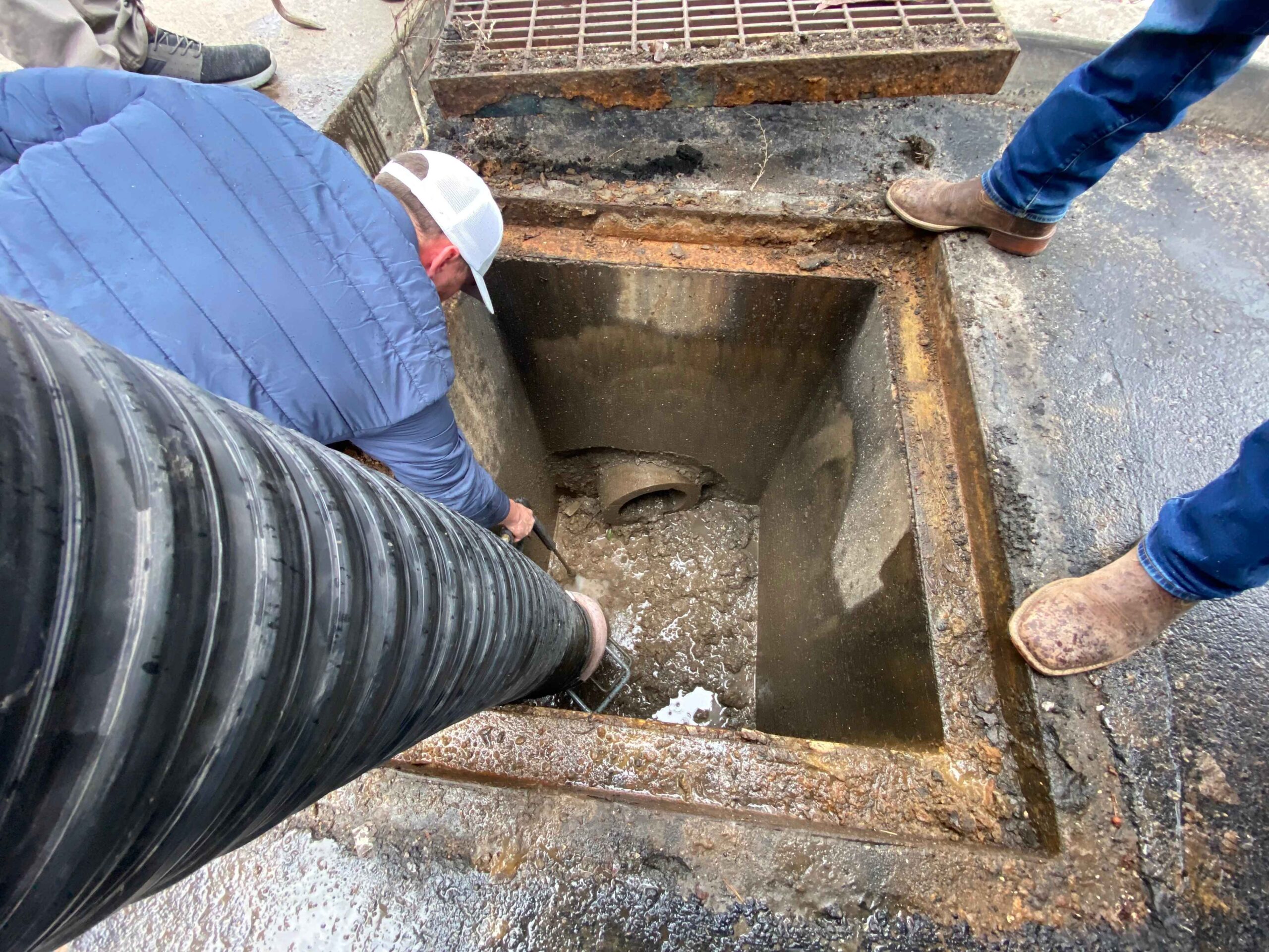 A man is positioned in a sewer, assessing a pipe, illustrating the work of erosion control services.