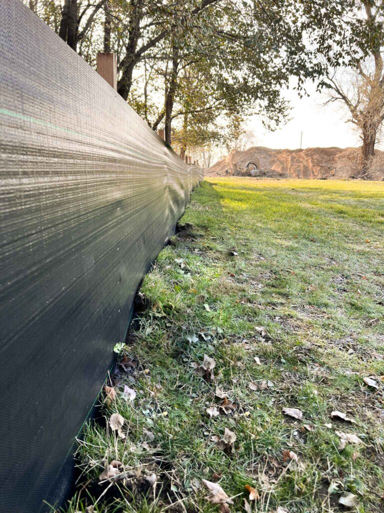 Close-up of a silt fence installed along the ground as part of erosion control services, ensuring soil stability during construction and land development