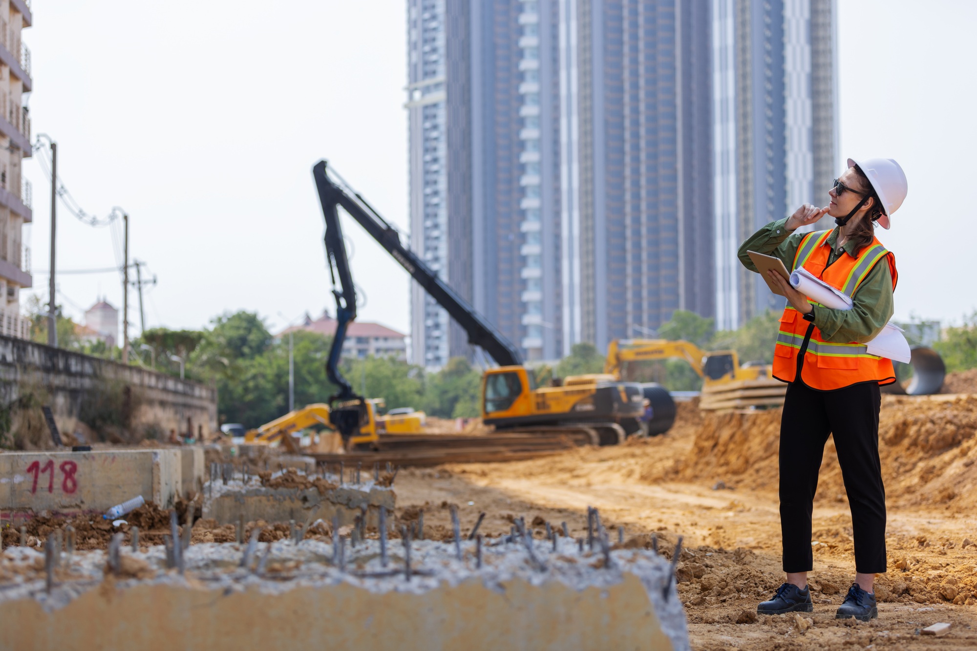 A female construction engineer using a tablet and blueprints.