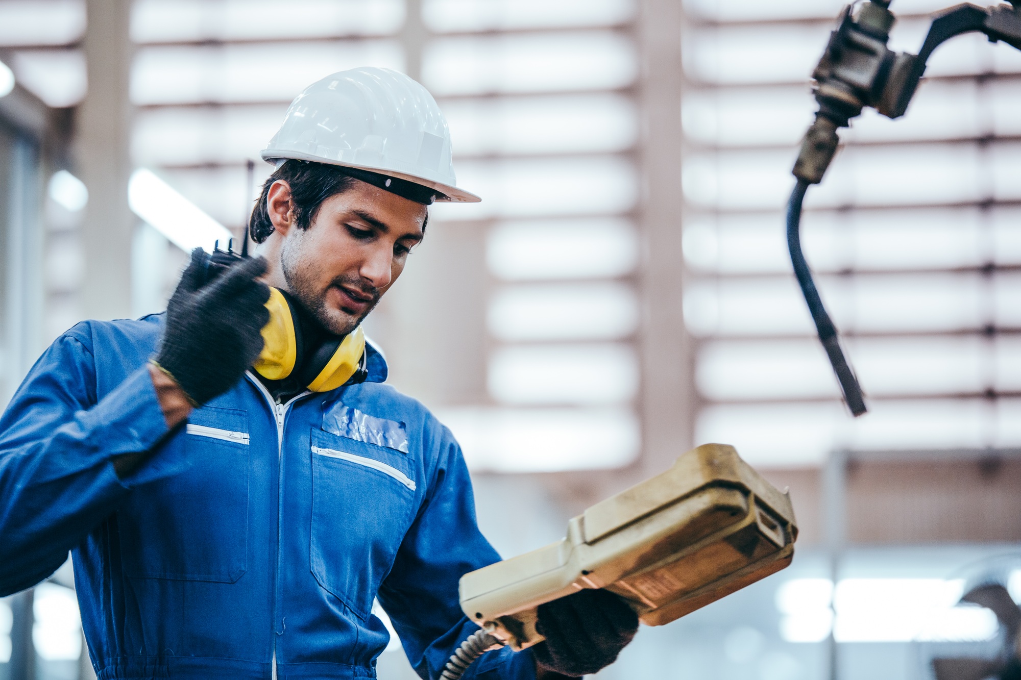 Construction worker using machine controller to control machine at the factory industry