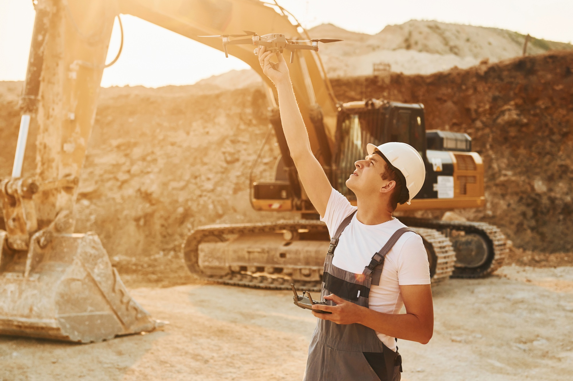 Control of the project. Worker in professional uniform is on the borrow pit at daytime