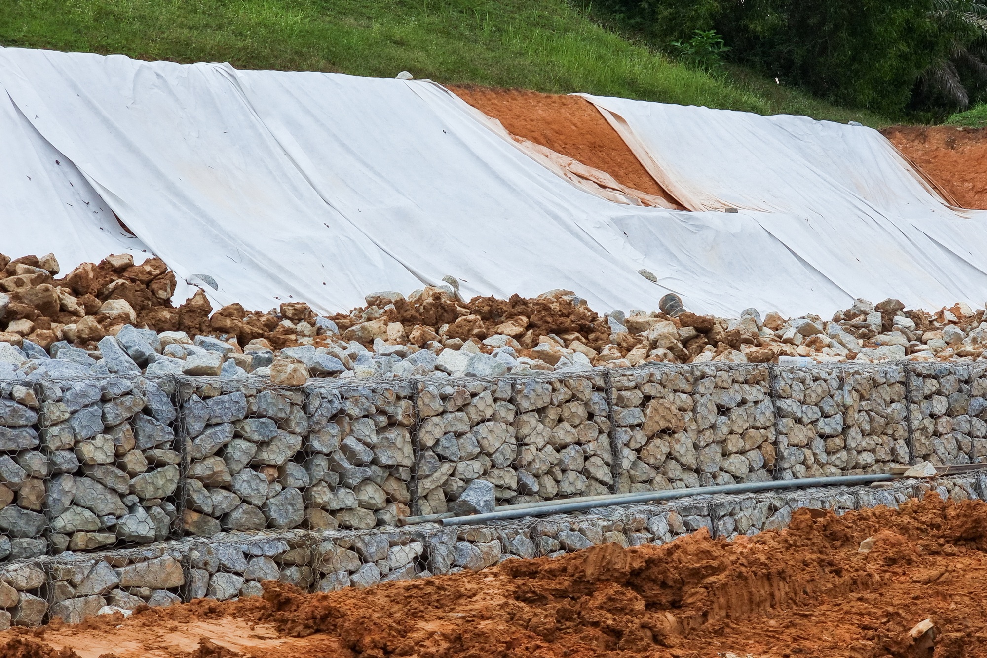 Series of close-up slope retention construction design with rocks and mesh to manage landslide