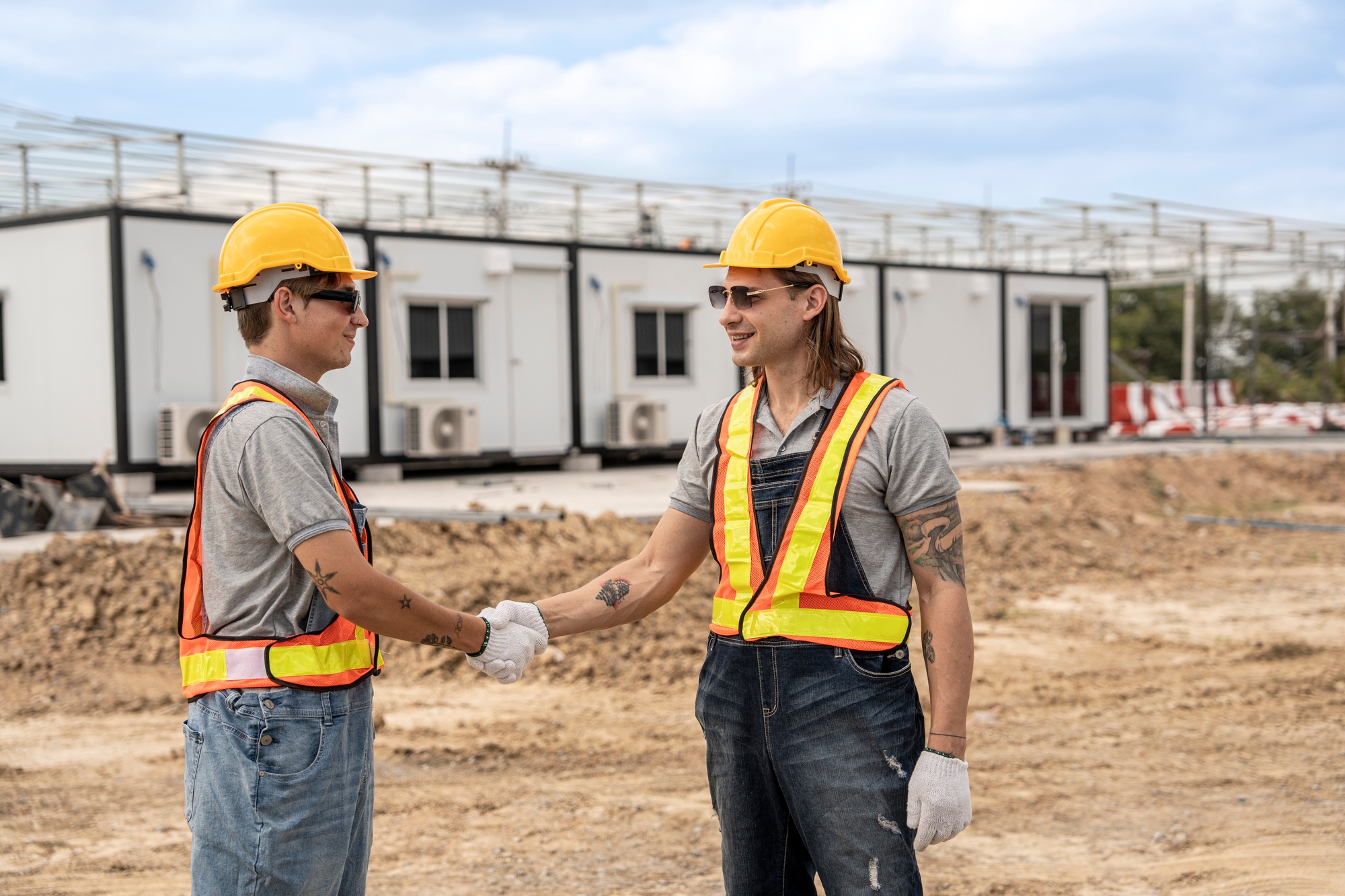 Two construction workers shaking hands at a construction site